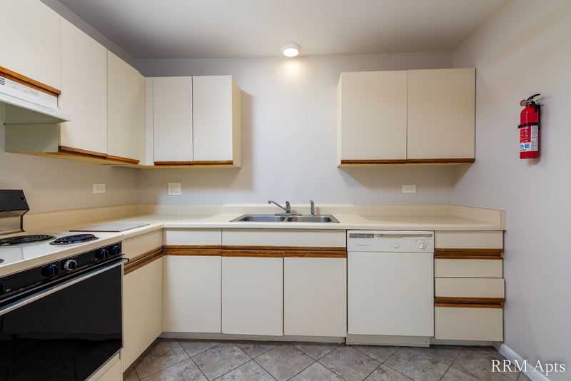 Kitchen with white oak-trimmed cabinets, black stove, white dishwasher, sink and tile floor, Pioneer Court apartment 900 3C