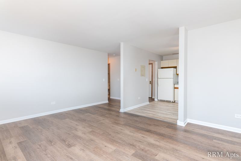 Living room with wood-look floor, a half wall and a hallway to the kitchen, Pioneer Court apartment 900-3D