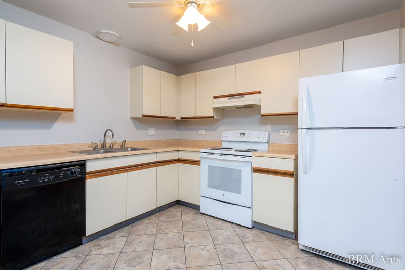 Kitchen with white oak-trimmed cabinets, black dishwasher, white stove and refrigerator, Pioneer Court apartment 918 1B