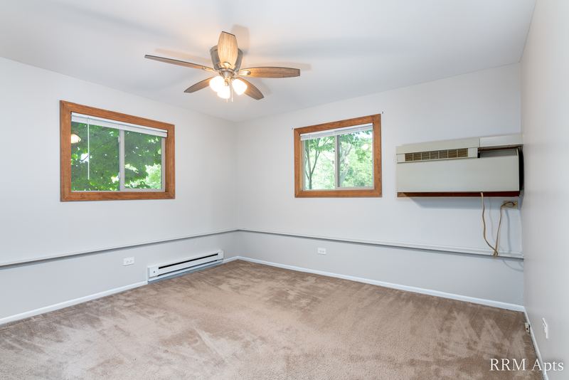 Empty room with beige carpet, two windows, ceiling fan and a wall air conditioner, Pioneer Court apartment 918-1E