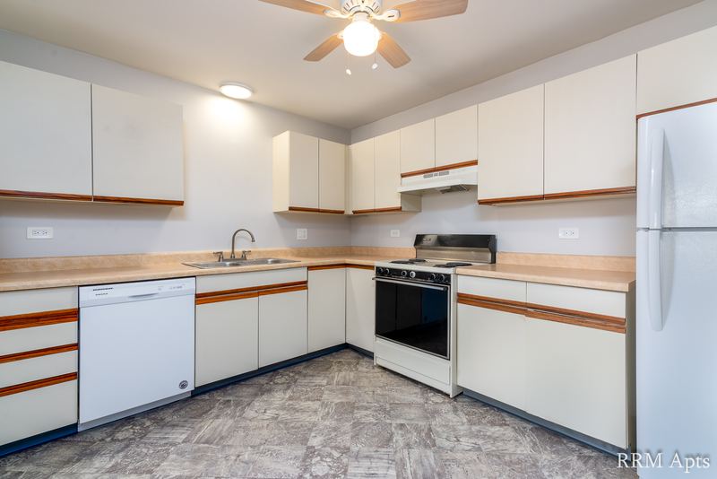 Kitchen with white cabinets, white refrigerator, stove and dishwasher, and gray vinyl floor, Pioneer Court apartment 918-1F
