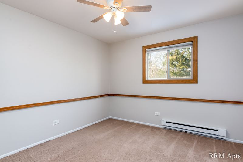 Empty room with beige carpet, one window with wood trim, chair rail and ceiling fan, Pioneer Court apartment 918-1F