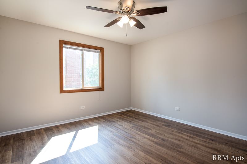 Bedroom with wood-look floor, ceiling fan, oak-trimmed window and a baseboard heater, Pioneer Court apartment 918 2A