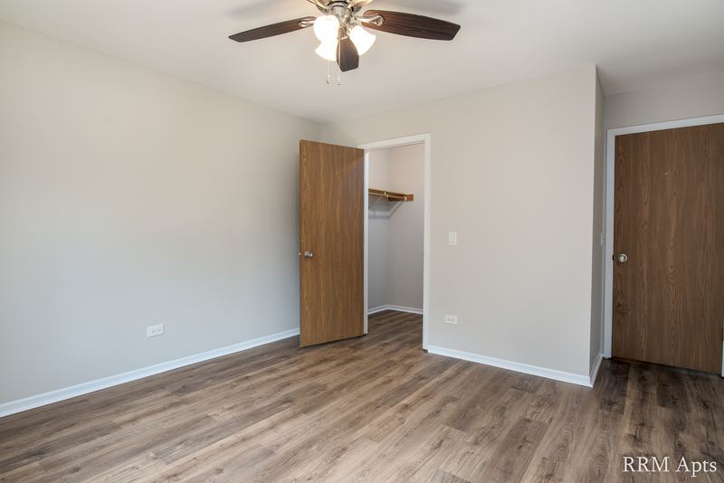 Bedroom with wood-look floor, ceiling fan, open closet with a shelf and an oak door, Pioneer Court apartment 918 2A