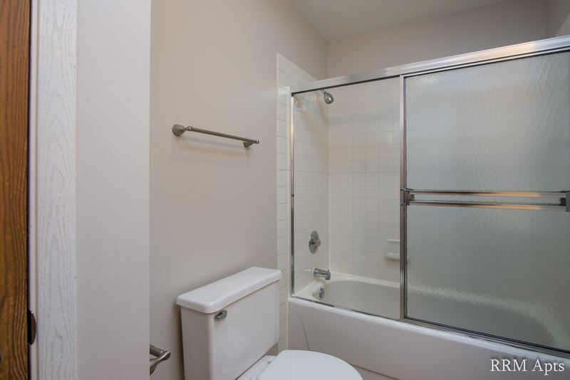 Bathroom with sliding glass tub doors, toilet and a towel bar, Pioneer Court apartment 918 2A