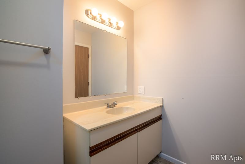 Bathroom with cream oak-trimmed vanity, mirror, light bar and a towel bar, Pioneer Court apartment 918 2A