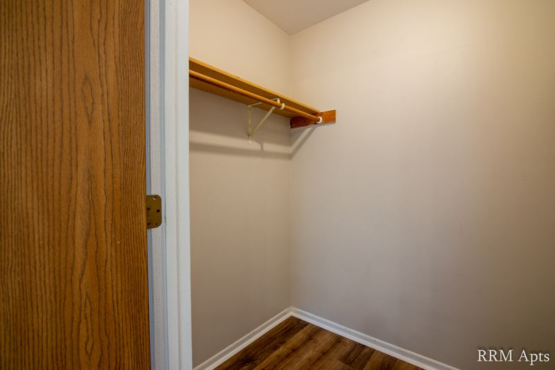 Closet with wood-look floor, oak door frame and a shelf with a hanging rod, Pioneer Court apartment 918 2A