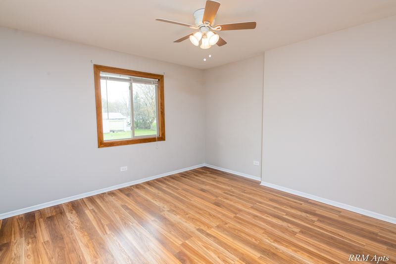 Empty room with wood floor, one wood-trimmed window and a ceiling fan, Pioneer Court apartment 918-2D