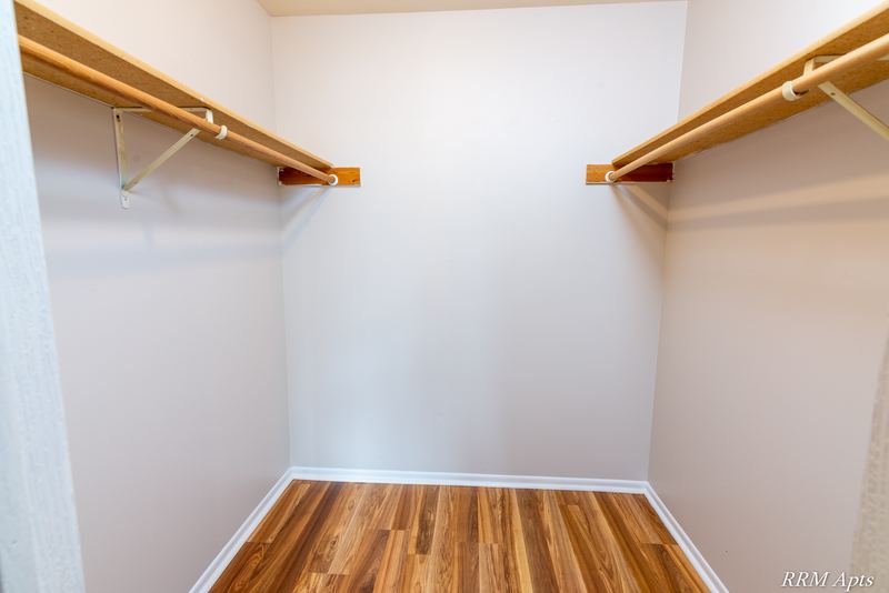 Closet with wood floor and shelves with hanging rods on both sides, Pioneer Court apartment 918-2D