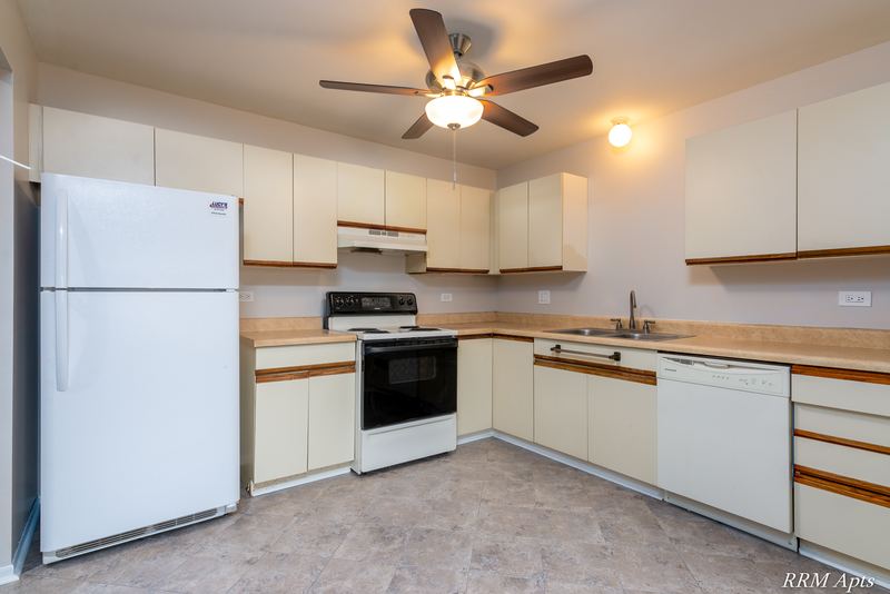 Kitchen with white oak-trimmed cabinets, white appliances and a ceiling fan, Pioneer Court apartment 918 2E