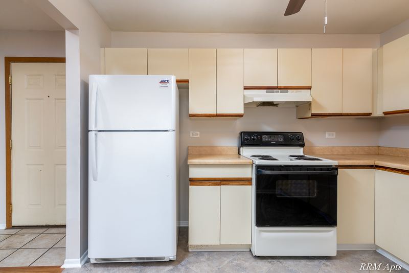 Kitchen with white oak-trimmed cabinets, white refrigerator, white stove and a white door, Pioneer Court apartment 918 2E