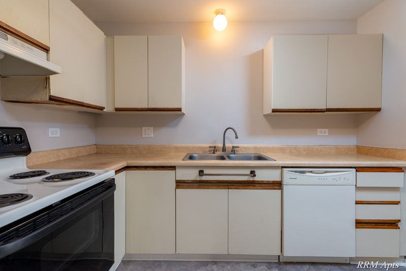 Kitchen with white oak-trimmed cabinets, black stove, range hood, sink and white dishwasher, Pioneer Court apartment 918 2E