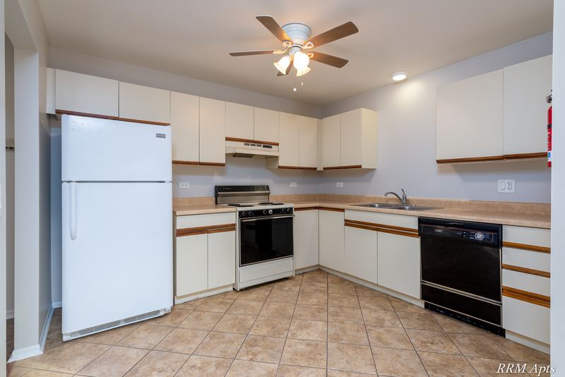 Kitchen with white oak-trimmed cabinets, white refrigerator, black stove and dishwasher, Pioneer Court apartment 918 3A