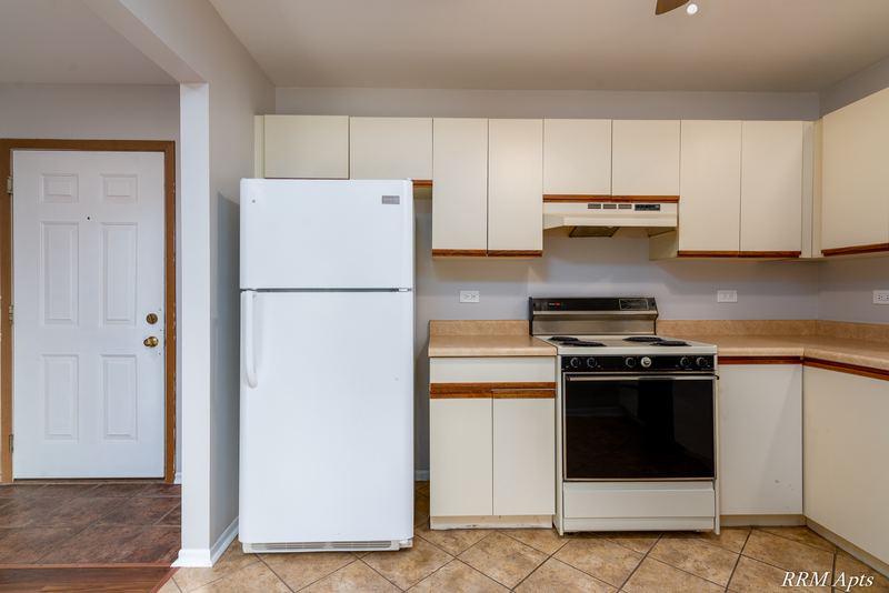 Kitchen with white oak-trimmed cabinets, white refrigerator, black stove and a white door, Pioneer Court apartment 918 3A