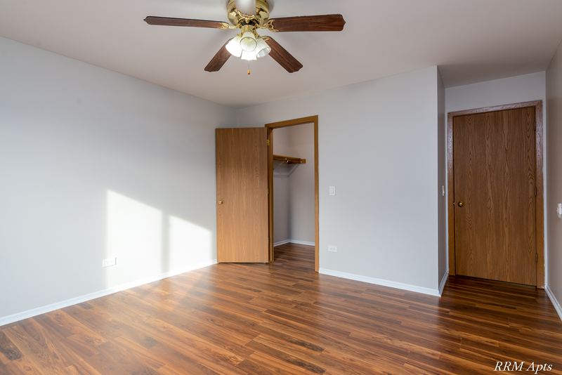 Bedroom with wood-look floor, ceiling fan, open closet and two oak doors, Pioneer Court apartment 918 3A