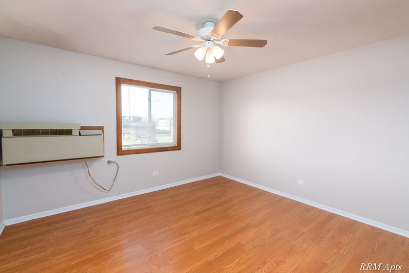 Living room with wood floor, wall air conditioner, wood-trimmed window and ceiling fan, Pioneer Court apartment 918-3C