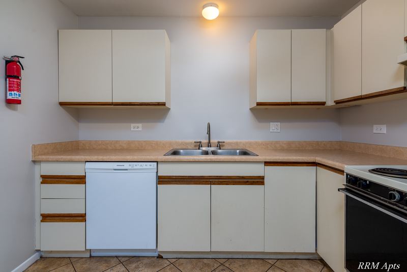 Kitchen with white oak-trimmed cabinets, white dishwasher, double sink and a black stove, Pioneer Court apartment 918 3F