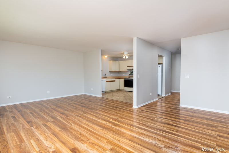 Living room with wood-look floor, a half wall and a view into the kitchen, Pioneer Court apartment 918 3F