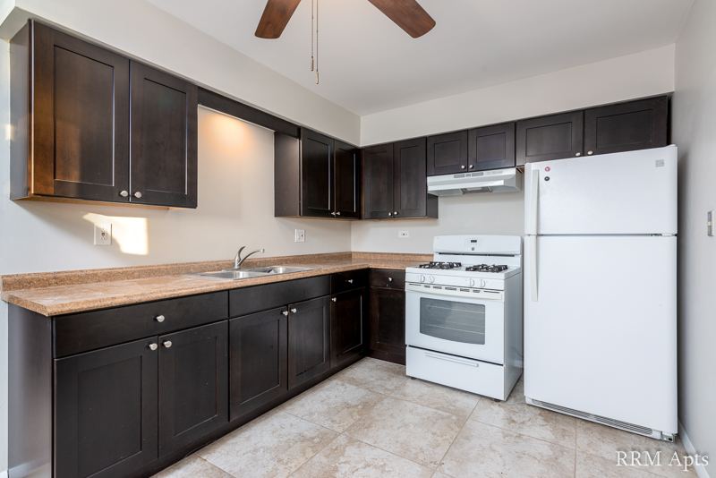 Kitchen with dark cabinets, white gas stove and refrigerator and tile floor, Pistakee Road apartment 1D