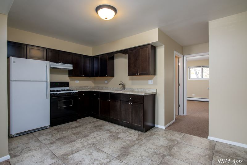 Kitchen with dark brown cabinets, white refrigerator, black stove, tile floor and a doorway, Pistakee Road apartment 2B