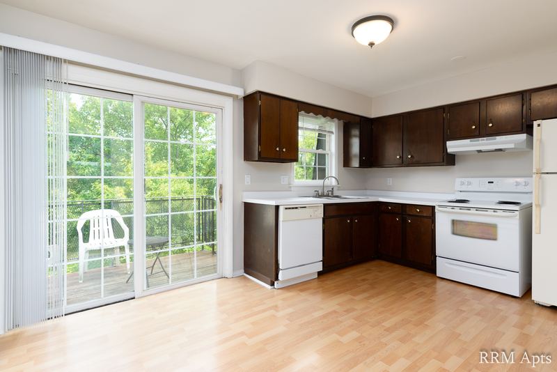Kitchen with dark brown cabinets, white stove, dishwasher and sliding door to a balcony, Prairie Ridge apartment 9716 2B
