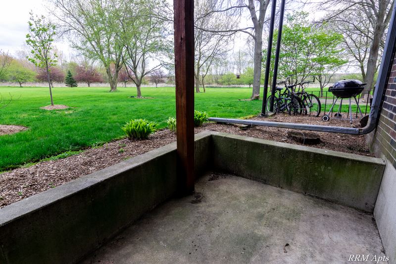Patio with concrete floor, low block wall and a view of lawn and trees, Prairie Ridge apartment 9716 GA