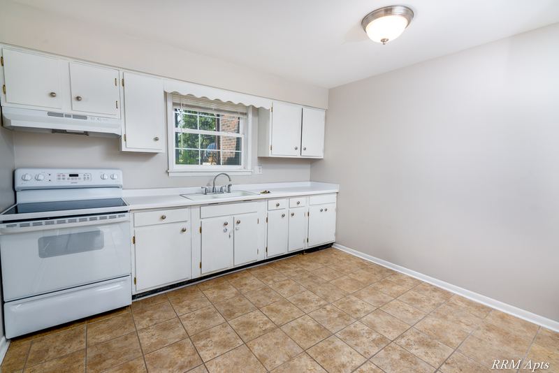 Kitchen with white cabinets, white electric stove, small window and tan tile floor, Prairie Ridge apartment 9716 GA