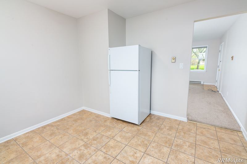Kitchen corner with white refrigerator and a doorway to a carpeted room with window, Prairie Ridge apartment 9716 GA