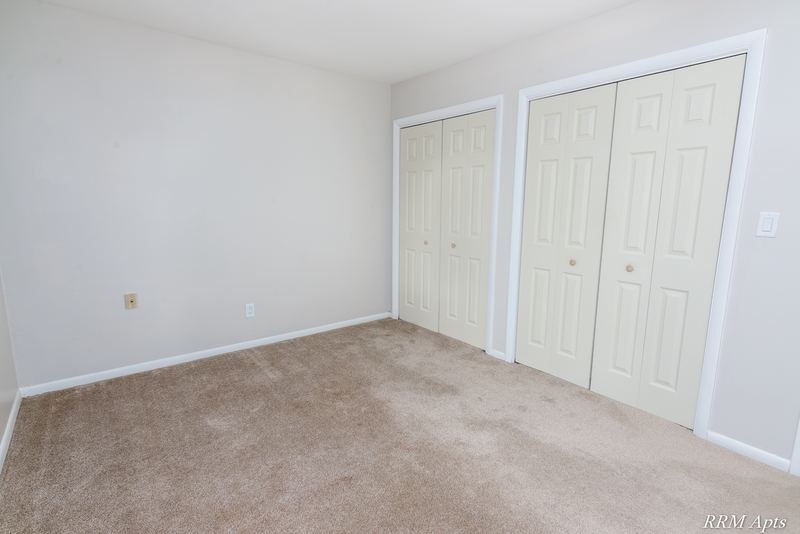Bedroom with beige carpet and two closets with white folding doors, Prairie Ridge apartment 9716 GA