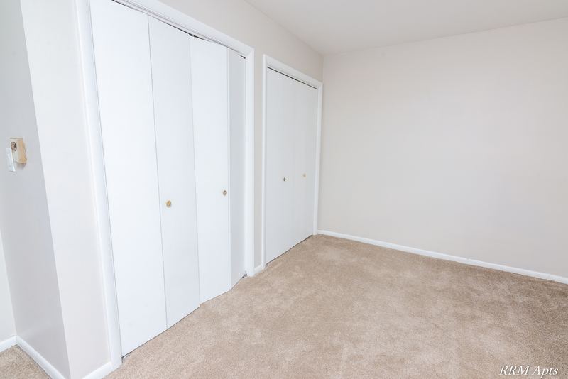 Bedroom with beige carpet, white folding closet doors and a doorway, Prairie Ridge apartment 9716 GA