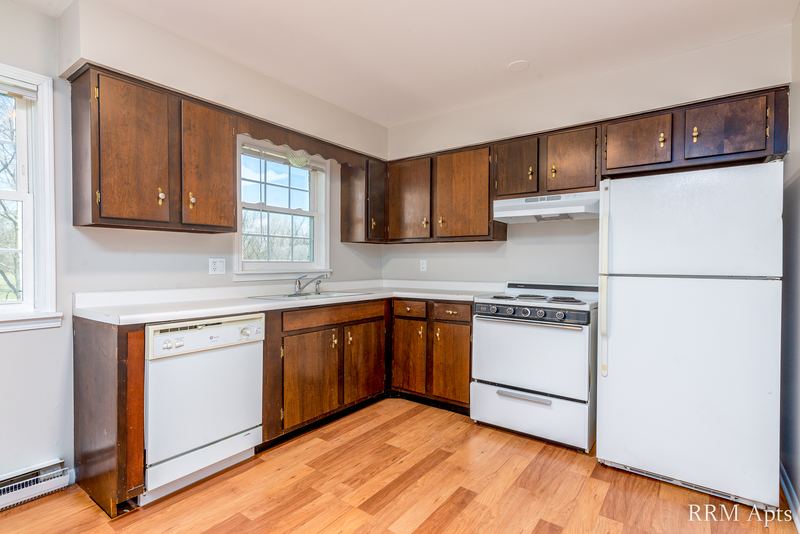 Kitchen with dark wood cabinets, white refrigerator, stove, dishwasher and wood floor, Prairie Ridge apartment 9718-1D