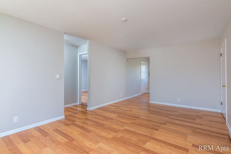 Living room with wood floor, bare walls and an opening to the hallway, Prairie Ridge apartment 9718-1D