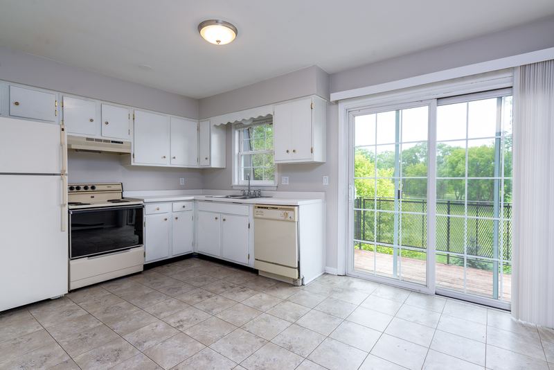 Kitchen with white cabinets, white stove, dishwasher, tile floor and a sliding glass door, Prairie Ridge apartment 9718 2C