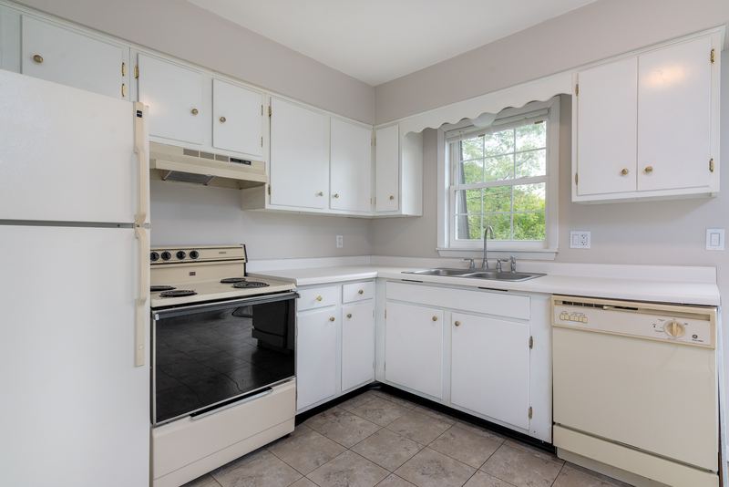 Kitchen with white cabinets, white refrigerator, stove and dishwasher, and a window, Prairie Ridge apartment 9718 2C
