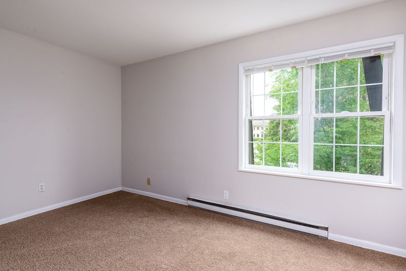 Empty room with beige carpet, window with trees outside and a baseboard heater, Prairie Ridge apartment 9718 2C