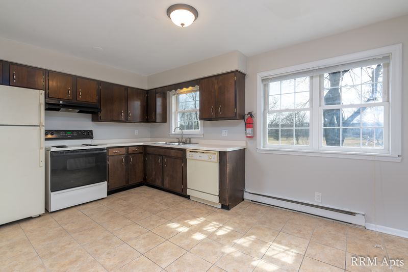 Kitchen with dark wood cabinets, white stove, dishwasher, tile floor and a window, Prairie Ridge apartment 9806 1A