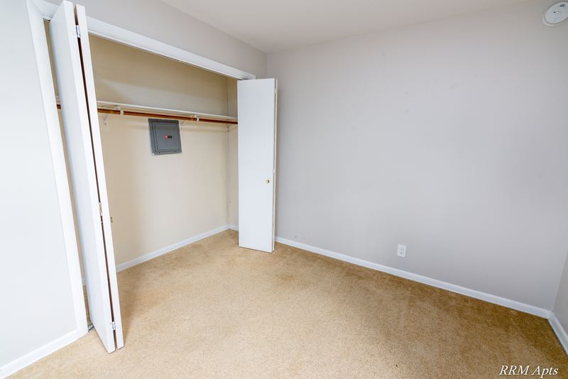 Bedroom with beige carpet and an open closet with folding doors and rod, Prairie Ridge apartment 9806-1B
