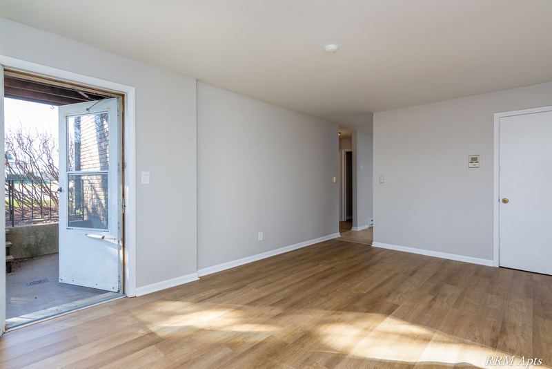 Living room with wood floor, glass door to a patio and a hallway to other rooms, Prairie Ridge apartment 9806 GA