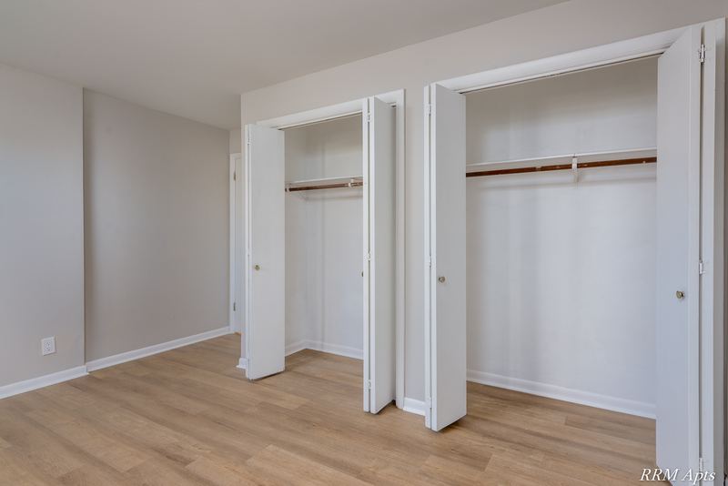 Bedroom with wood floor and a pair of open closets with folding doors, Prairie Ridge apartment 9806 GA