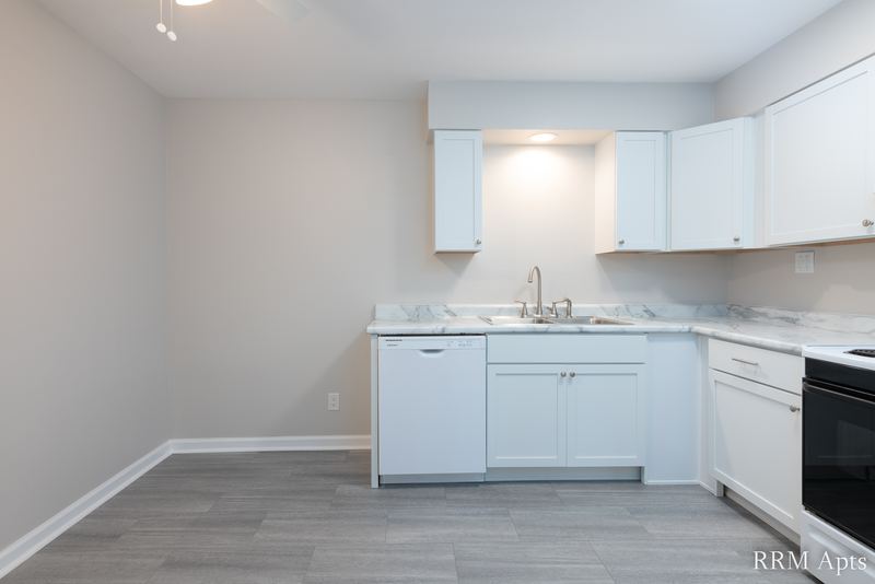 Kitchen with white cabinets, marble-look counter and gray wood-look floor, Prairie Ridge apartment 9810 GB
