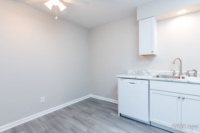 Kitchen with white cabinets, white dishwasher, sink with marble-look counter and gray floor, Prairie Ridge apartment 9810 GB