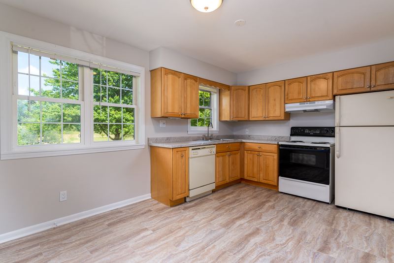 Kitchen with light oak cabinets, white refrigerator, stove and dishwasher, and a window, Prairie Ridge apartment 9812 1D