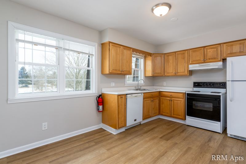 Kitchen with light oak cabinets, white dishwasher and stove, window and a fire extinguisher, Prairie Ridge apartment 9812 2D
