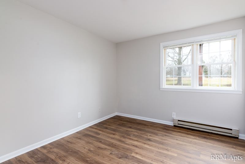 Bedroom with two windows, baseboard heater and wood-look floor, Prairie Ridge apartment GC
