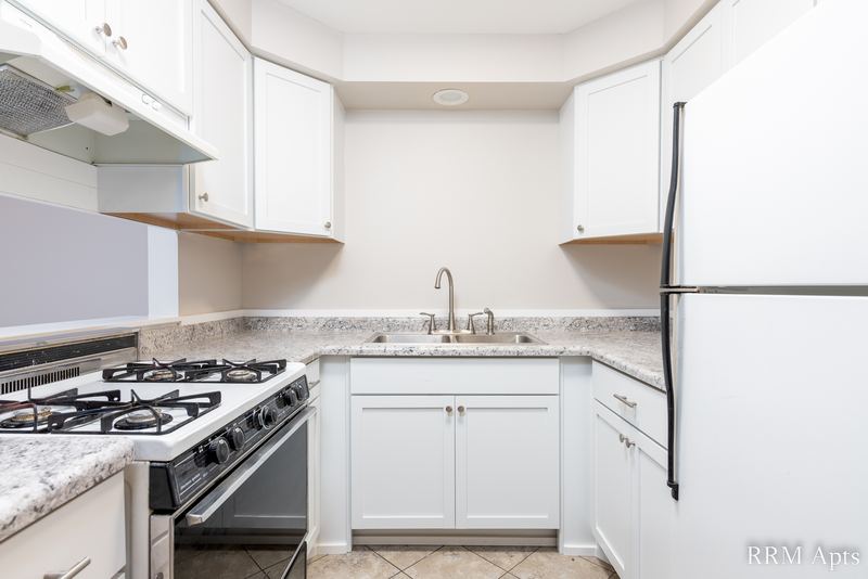 Kitchen with white cabinets, stainless gas stove, white refrigerator and granite-look counter, Slusser Street apartment 1