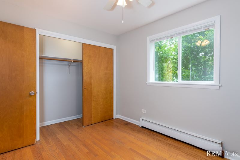 Bedroom with wood floor, wood door, open closet with sliding wood doors and a window, Slusser Street apartment 1