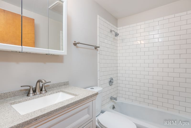 Bathroom with white vanity, granite-look counter, mirrored cabinet and subway tile tub, Slusser Street apartment 1