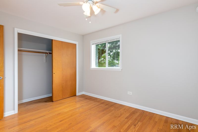 Bedroom with wood floor, ceiling fan, window and open closet with wood sliding door, Slusser Street apartment 1