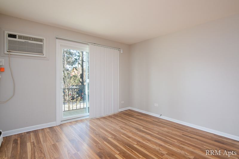 Living room with hardwood floor, sliding glass door and wall air conditioner, Slusser Street apartment 3