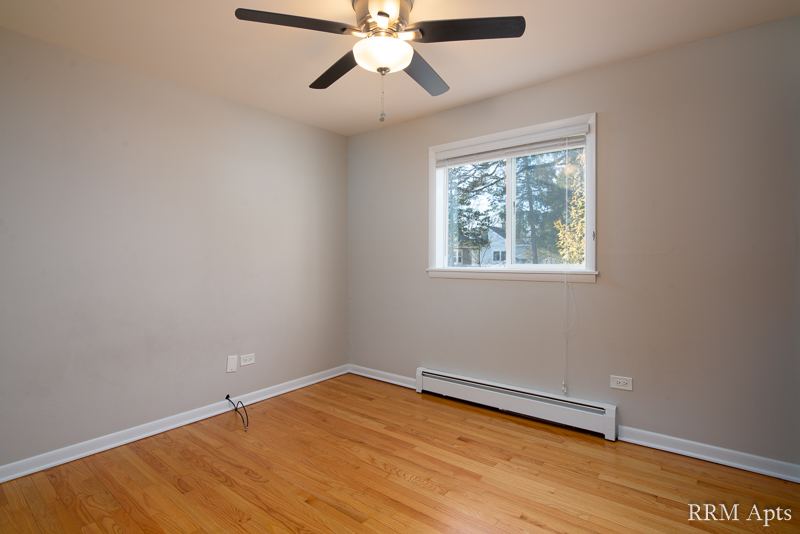 Bedroom with ceiling fan, window, baseboard heater and hardwood floor, Slusser Street apartment 3